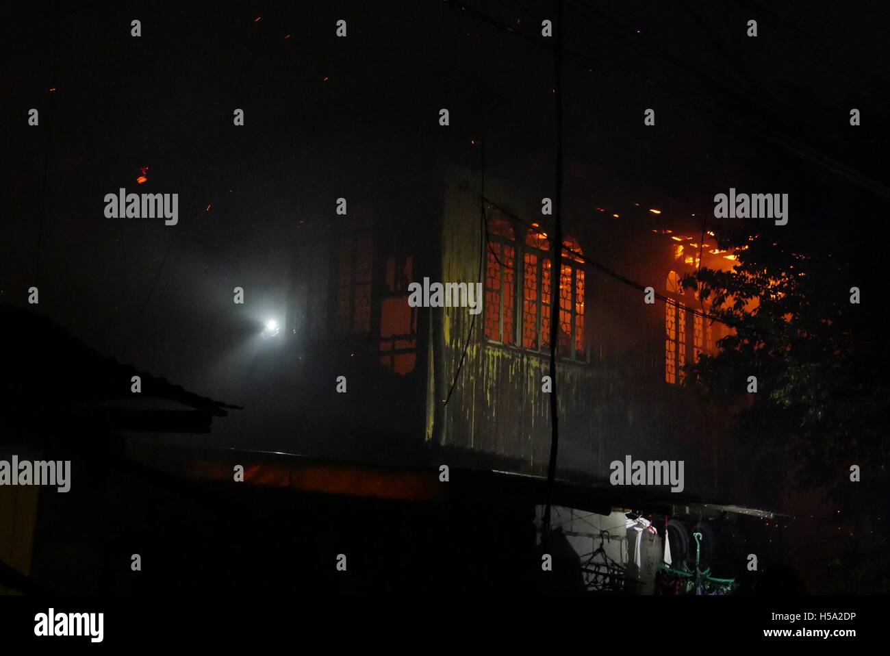 Mandaluyong, Philippinen. 20. Oktober 2016. Ein Feuerwehrmann auf der Seite dieses Hauses mit einer Taschenlampe versucht in das brennende Haus zu erhalten und das Feuer in ihm zu töten. Bildnachweis: George Buid/Pacific Press/Alamy Live-Nachrichten Stockfoto