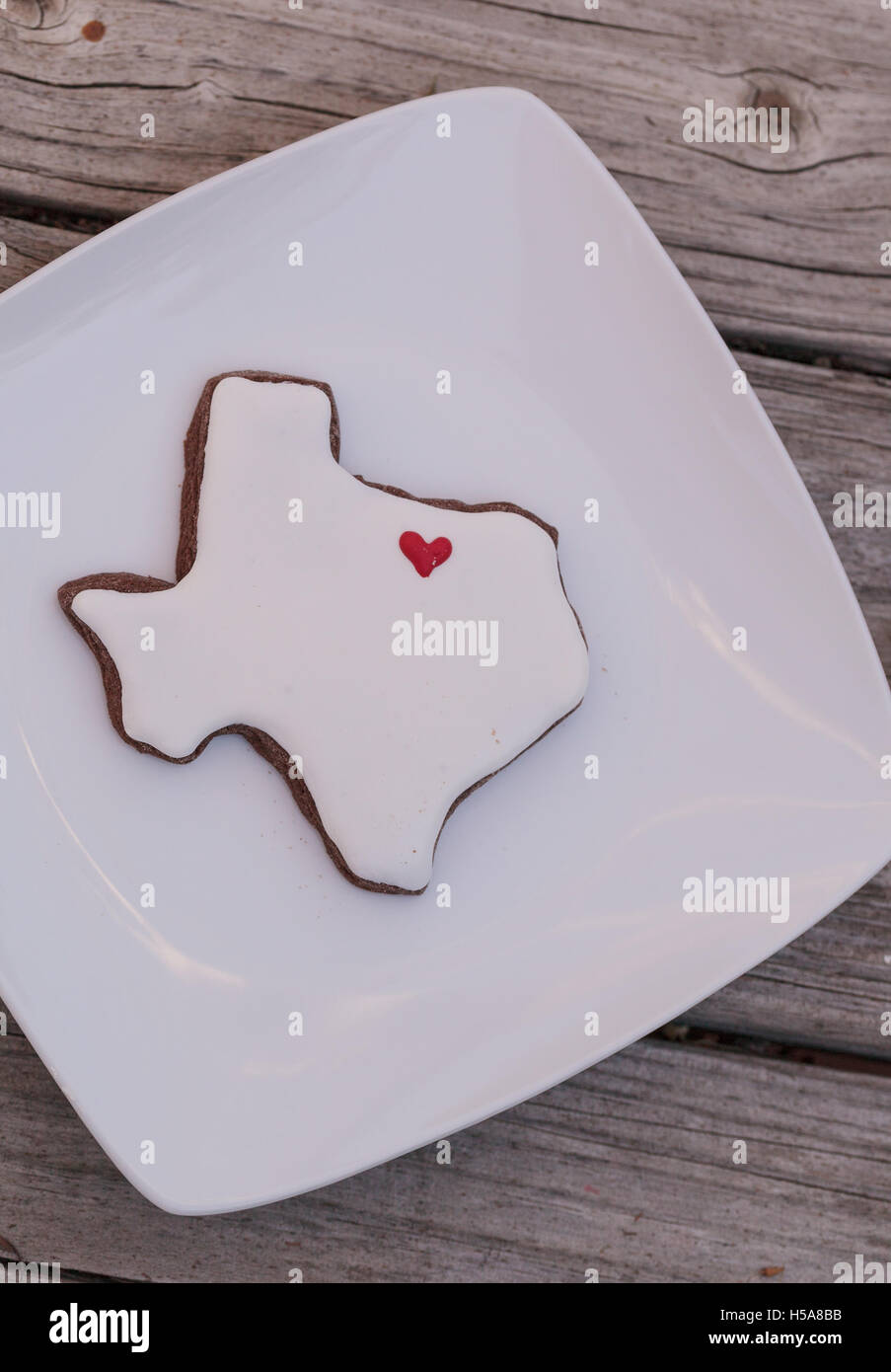 Texas hat Zucker Cookie mit weißer Glasur und ein rotes Herz auf einem rustikalen Holztisch geprägt. Stockfoto