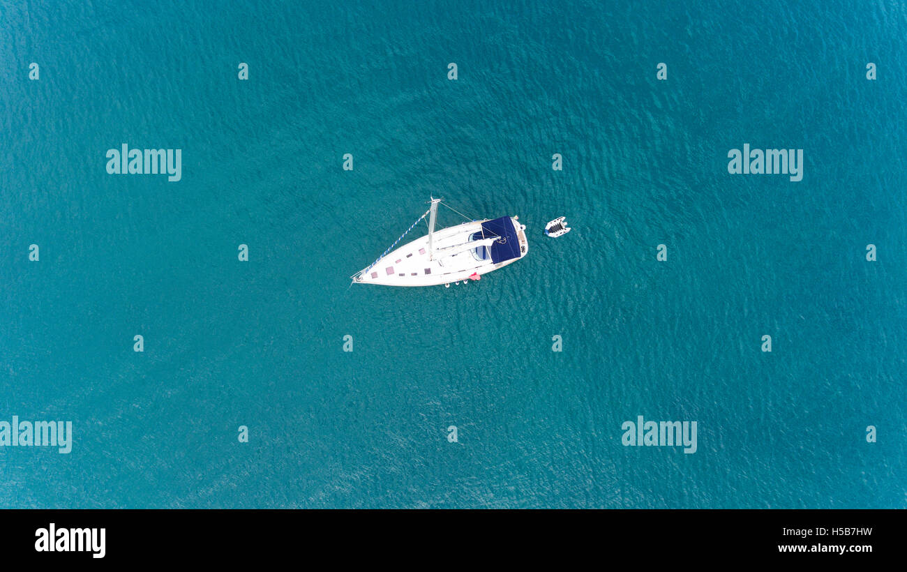 Draufsicht der Segelyacht mit einer kleinen Ponton mitten im ruhigen Meer Türkis, grüne Wasser schweben Stockfoto