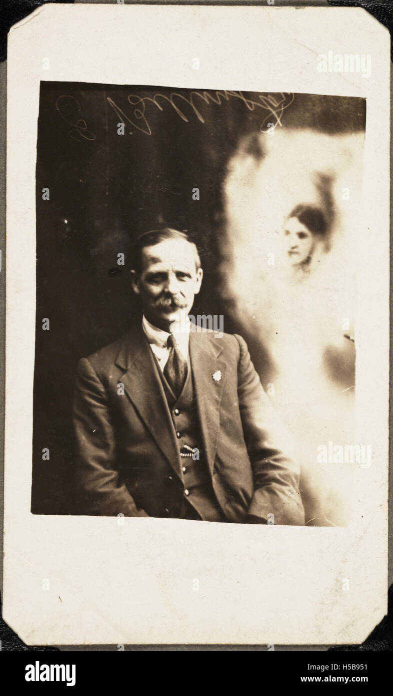 Ein Mann wird auf einem historischen Foto dargestellt, möglicherweise symbolisch, das den Geist oder die Erinnerung an seine verstorbene erste Frau trägt. Dieses Bild kann kulturelle oder persönliche Ausdrücke von Trauer oder Erinnerung widerspiegeln. Stockfoto