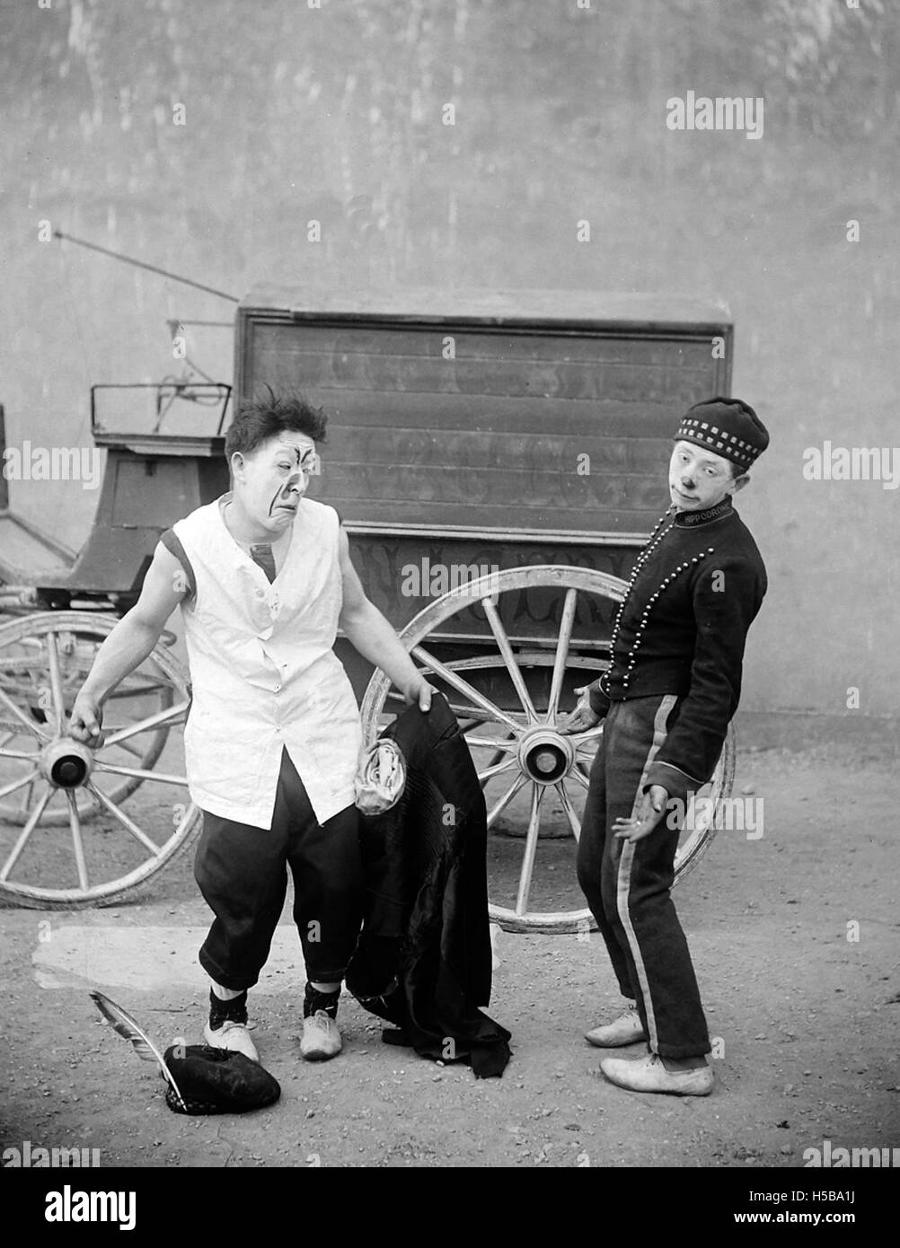 Zwei Clowns stehen vor einem Zirkuswagen, typisch für Zirkusaufführungen des frühen 20. Jahrhunderts. Das Bild spiegelt die Unterhaltungskultur und die lebhafte Natur der Zirkusse während dieser Zeit wider. Stockfoto