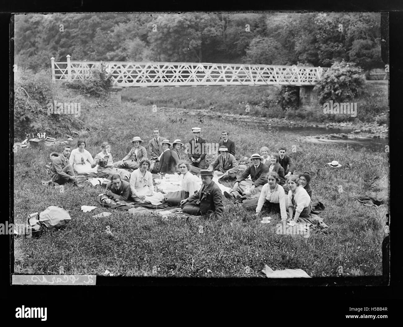 Bild von Einzelpersonen, die in der Nähe einer Brücke picknicken, veranschaulicht Freizeitaktivitäten in einer malerischen Umgebung im Freien. Stockfoto
