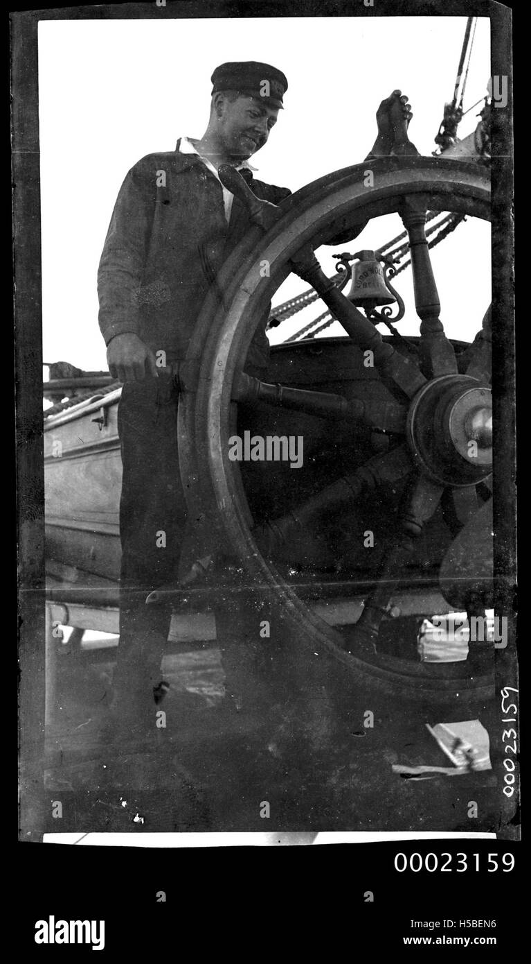 Ein Besatzungsmitglied ist am Schiffsrad der E R Sterling abgebildet, das die Verantwortung für die Navigation und Lenkung des Schiffes zeigt. Das Bild zeigt die entscheidende Rolle der Besatzungsmitglieder im Seeverkehr. Stockfoto