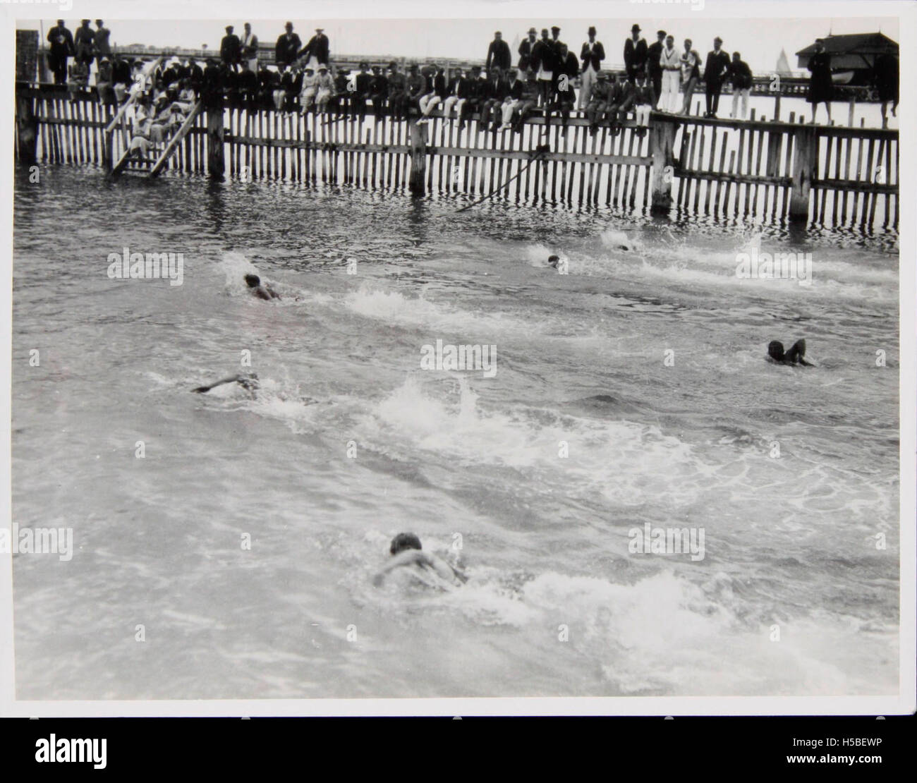 Ein Schwimmrennen in den Harbour Baths, bei dem es wahrscheinlich um Wettkämpfe zwischen den lokalen Schwimmern geht. Die Lage bietet einen Blick auf die Uferpromenade, was zur Gemeinschaftsatmosphäre und zur Beliebtheit von Wassersportarten in der Gegend beiträgt. Stockfoto