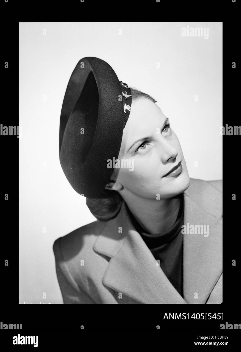 Dieses Foto zeigt eine Frau, die 1949 einen Hut modelliert und die Modetrends der Epoche hervorhebt. Das Bild zeigt den Stil der Nachkriegszeit und die Popularität von Hüten als Accessoire in den späten 1940er Jahren Stockfoto