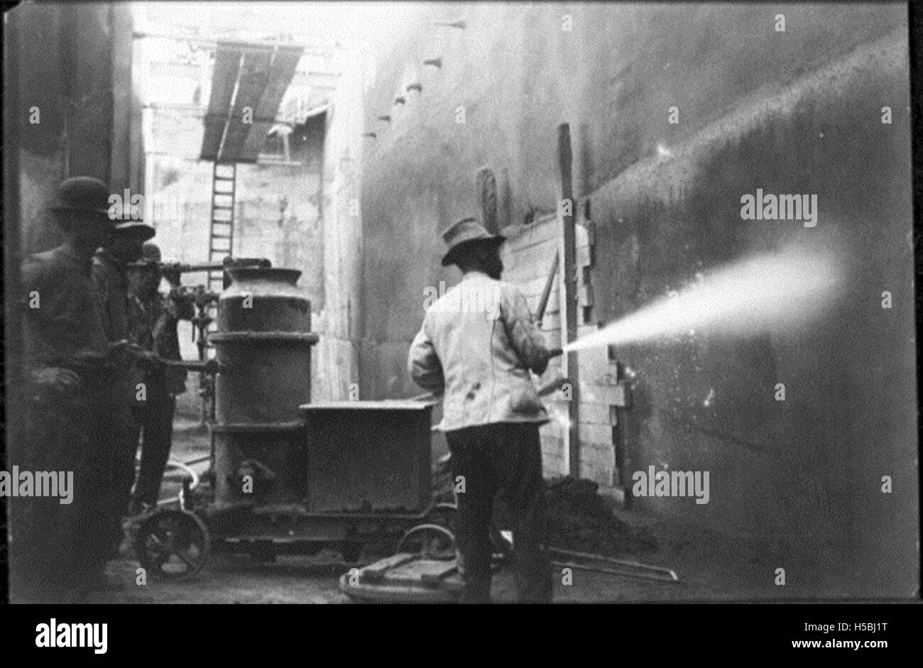Arbeiter werden gezeigt, wie sie den Schiffsrumpf reinigen, während sie an einem Trockendock angedockt sind, eine wichtige Instandhaltungsaufgabe in der maritimen Industrie. Stockfoto