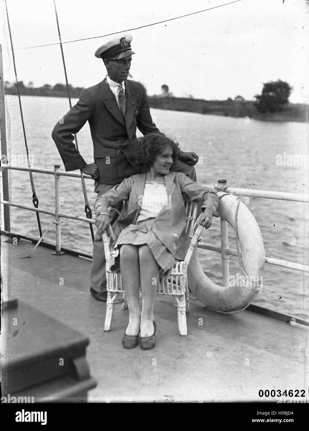Ein Foto aus den 1920er bis 1930er Jahren zeigt einen Marineoffizier, möglicherweise aus der Royal Australian Naval Reserve, und eine Frau, die auf Deck eines Schiffes sitzt. Dieses Bild spiegelt die Seekultur und das Leben auf See während dieser Zeit wider. Stockfoto