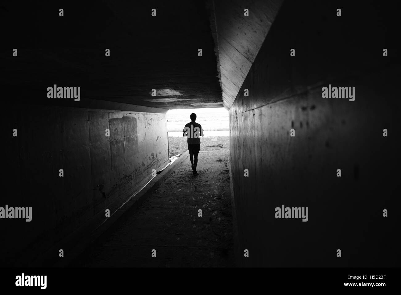 Kantigen schwarz-weiß Foto eines Mannes zu Fuß durch einen tunnel Stockfoto