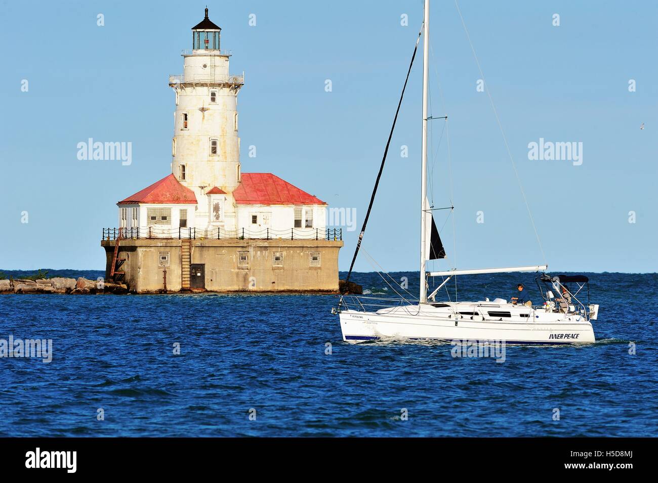 Ein Segelboot vorbei vor der Chicago Hafen Leuchtturm an einem Sommerabend wie es spiegelt dies wider. Chicago, Illinois, USA. Stockfoto