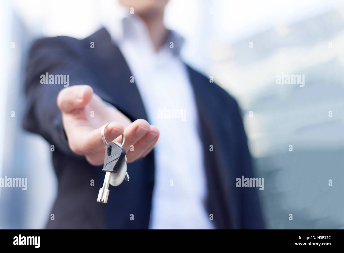 Immobilien-Makler die Schlüssel mit Gebäuden Hintergrund Stockfoto