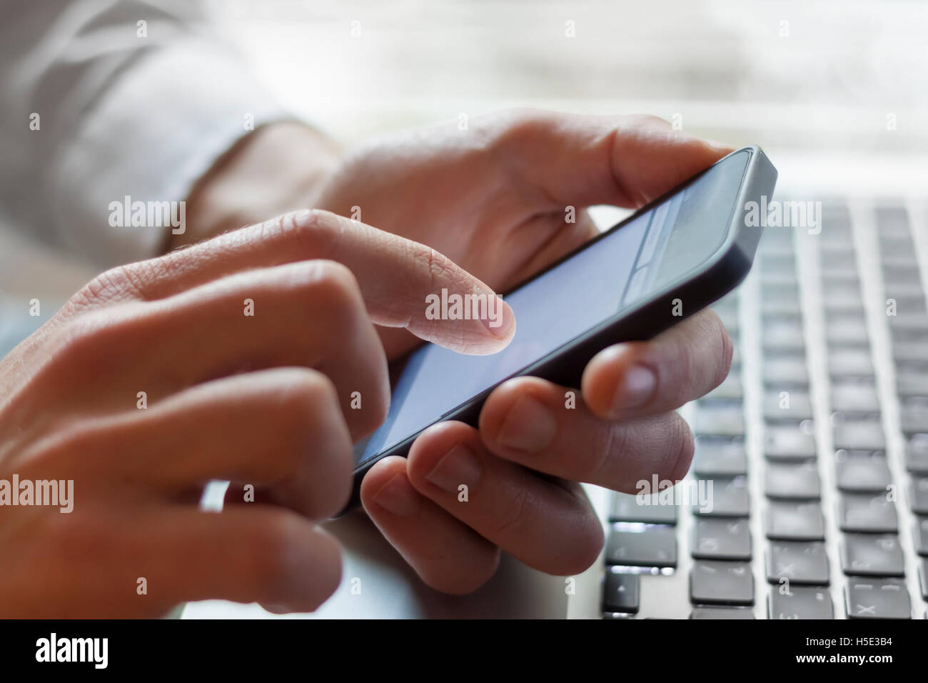 Leader Kontaktaufnahme mit seinem Business Team mit Smartphone und Laptop zur Hand Stockfoto