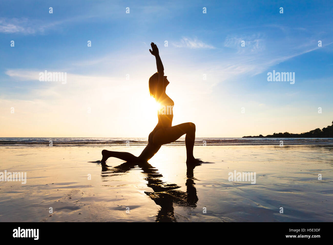 Junge passende Frau Yoga am Strand bei Sonnenaufgang für gesunden Lebensstil Stockfoto