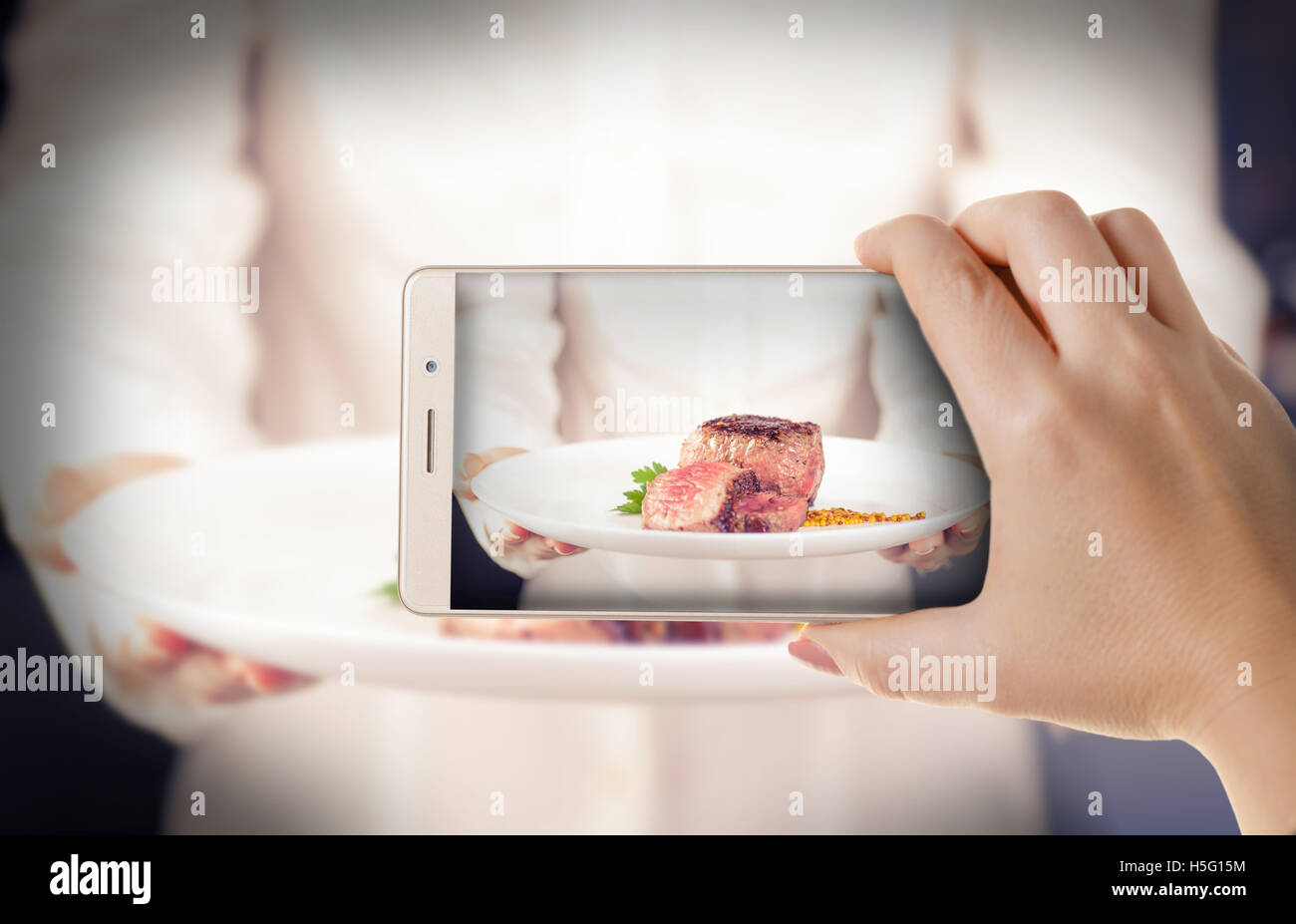 Hand mit dem Telefon schließen-up.woman fotografiert die gekochte Fleisch mit einem smartphone Stockfoto