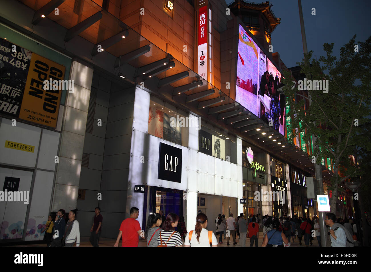 Abend, Wirtschaftsimperialismus, Chinesen und Touristen Fuß entlang der Wangfujing Street und den internationalen eleganten Geschäften. Stockfoto