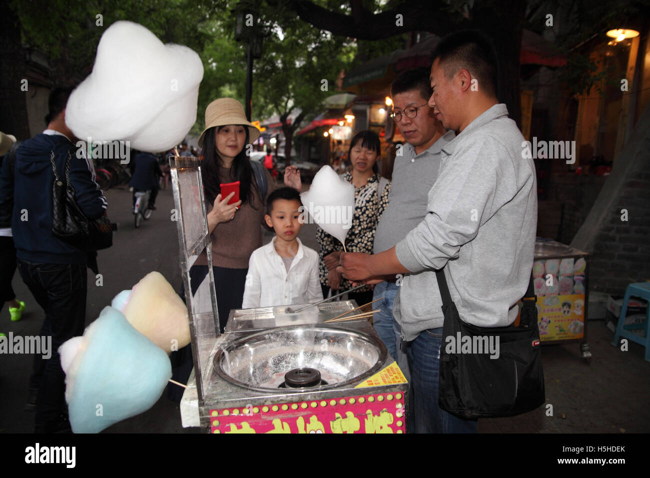 Eine chinesische Hausierer ist eine frisch gemachte weiße Zuckerwatte zu einem Kind übergeben, der mit seinen Eltern und seiner Großmutter wartet. Stockfoto