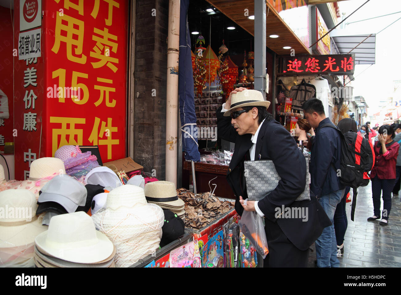 Ein chinesischer Mann versucht eine neue Mütze will er in einem Hut-Geschäft kaufen. Qibao Old Street, Beijing, China. 26.04.2016 Stockfoto