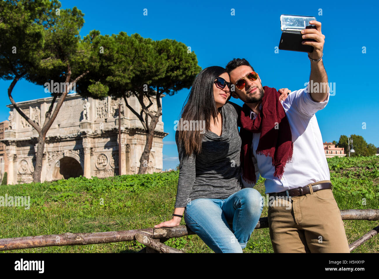 Kaukasische Pärchen nehmen ein Selbstporträt mit einem Smartphone vor dem Konstantinsbogen, Rom, Latium, Italien Stockfoto