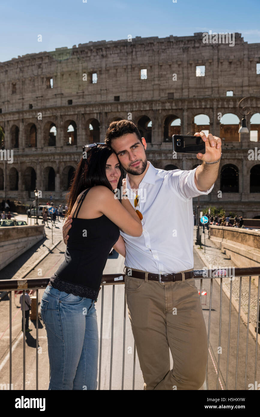Kaukasische Pärchen nehmen ein Selbstporträt mit einem Smartphone vor dem Kolosseum, Rom, Latium, Italien Stockfoto