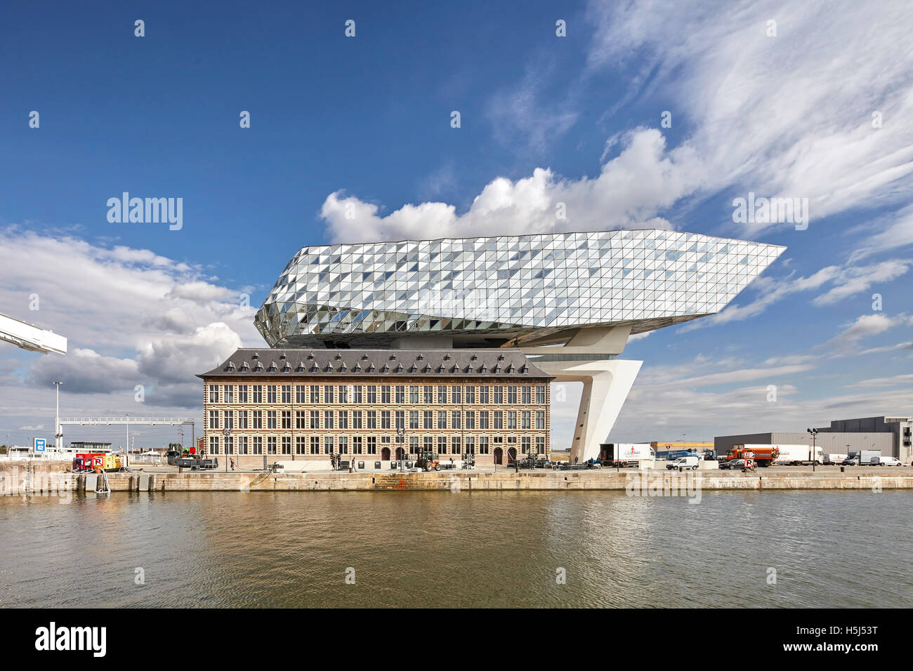 Frontale Ansicht von alt und neu über Wasser. Portweinhaus, Antwerpen, Belgien. Architekt: Zaha Hadid Architects, 2016. Stockfoto
