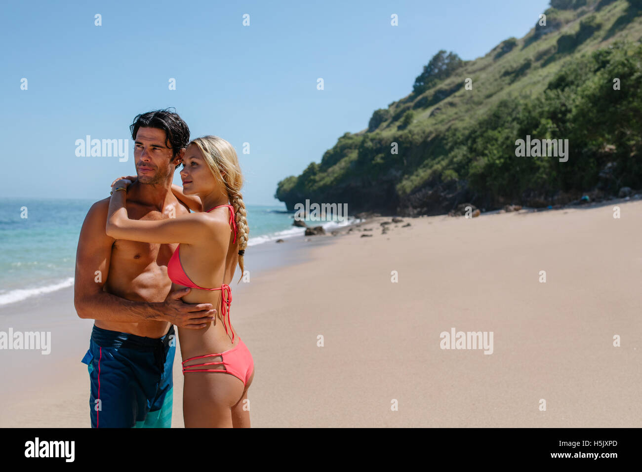 Porträt von schönen jungen Ehepaar stehen zusammen am Strand und auf der Suche nach. Frau im Bikini und Mann in Badehose auf th Stockfoto
