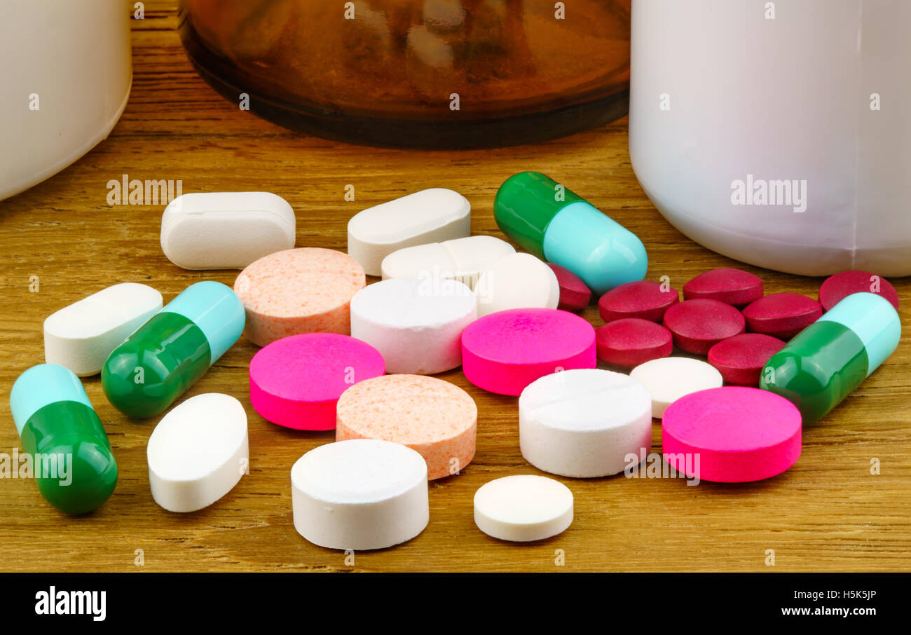 Bunte Pillen und Kapseln auf einem Holztisch Stockfoto