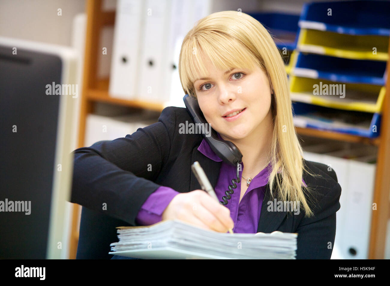 Junge Frau, kaufmännische Angestellte am Telefon und Notizen Stockfoto