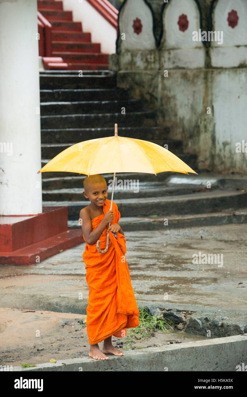 Junger Mönch mit einem Regenschirm im Regen, Dimbulagala buddhistische Kloster in der Nähe von Polonnaruwa, Sri Lanka Stockfoto