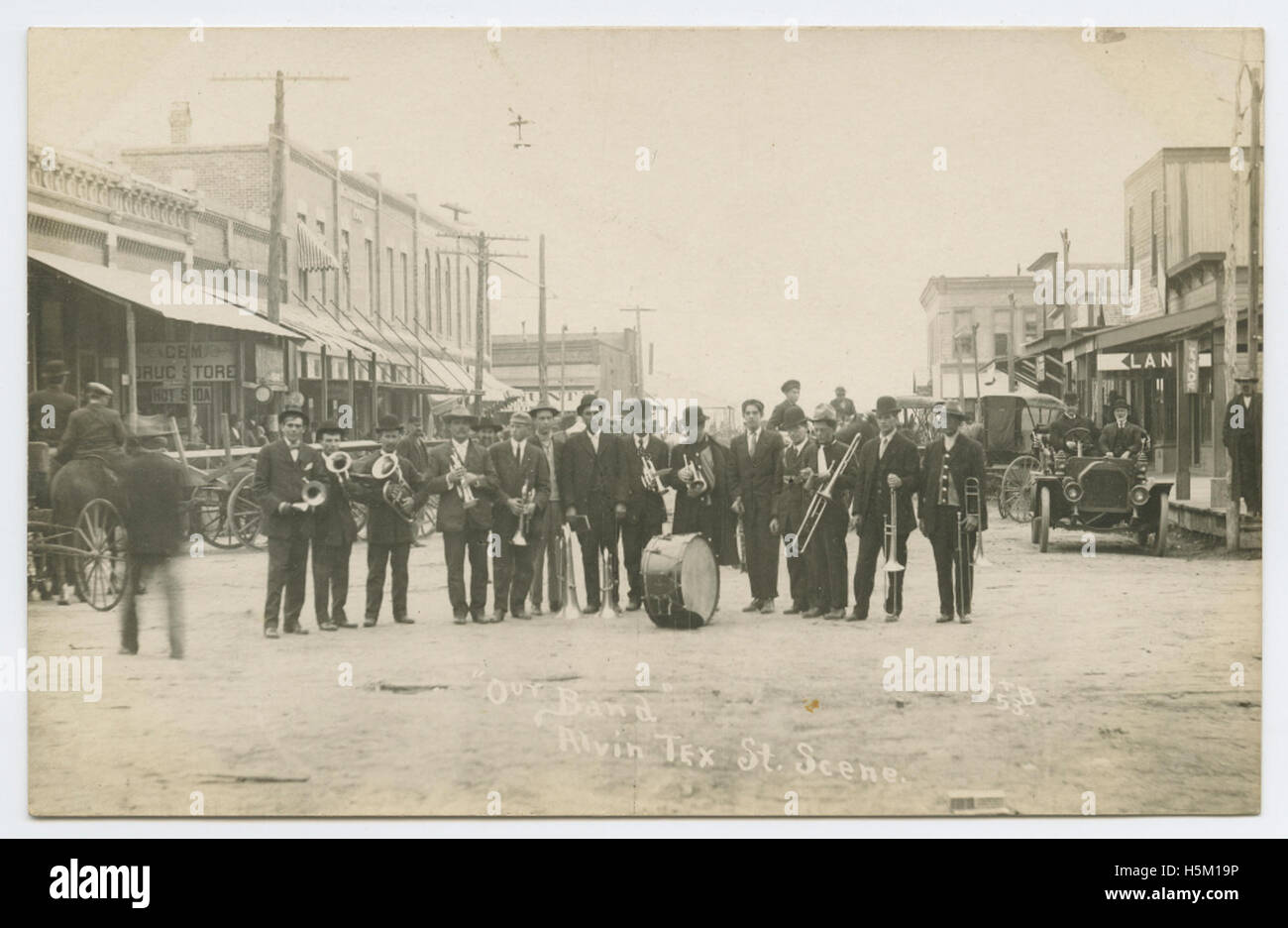 Eine echte Fotopostkarte (RPPC), die „Our Band“ aus Alvin, Texas, zeigt und eine Straßenszene in der Stadt mit Bands und lokalen Einzelhandelsgeschäften feststellt. Das Bild bietet eine Momentaufnahme des Stadtlebens und zeigt Musik, Handel und Gemeinschaft in einer kleinen amerikanischen Stadt. Stockfoto