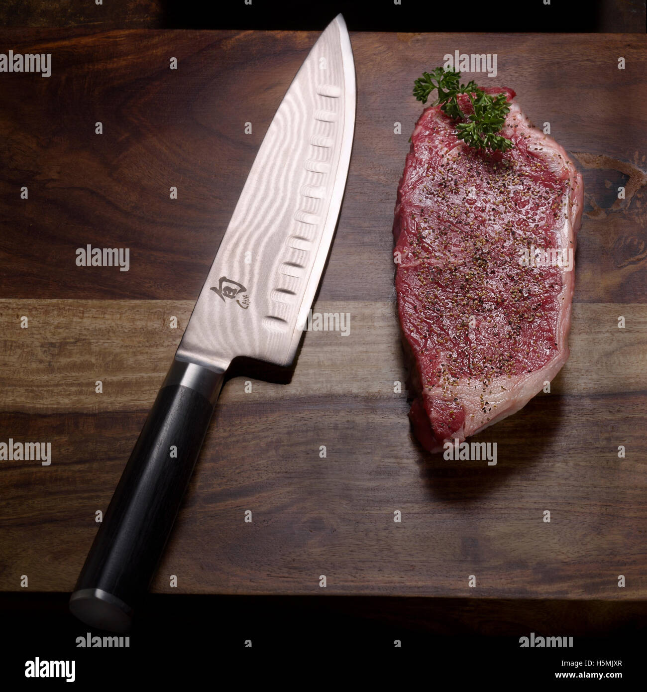 Rohes Rippenaugensteak und ein Messer auf einem Holztisch Stockfoto