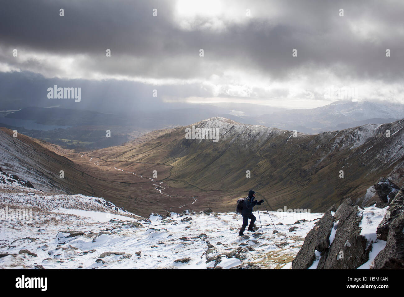 Eine Gehhilfe verwendet Wanderstöcke über Hart-Felsen, in der Nähe von Fairfield im Winter mit Heron Hecht und Nab Narbe in der Zeitmessung zu navigieren Stockfoto