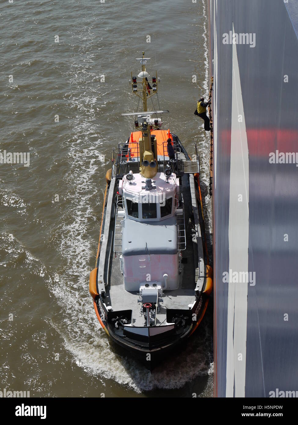 Ein Pilot an Bord kommen von einem riesigen Containerschiff steigt entlang der Rumpf auf See von Hamburg Stockfoto