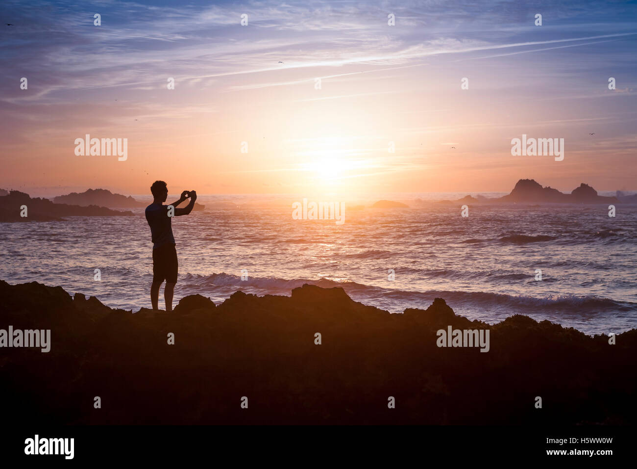 Junge Erwachsene nehmen Foto von erstaunlichen Abendlicht am Strand Stockfoto