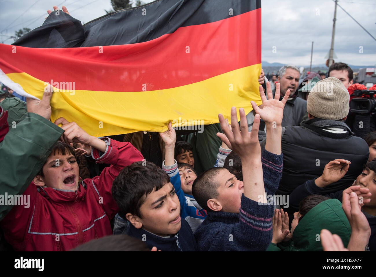 Flüchtling Jungen halten eine deutsche Flagge, die als Flüchtlinge und Migranten anspruchsvolle demonstrieren für die Europäische Union Grenzen zu öffnen, in die Flüchtlingslager von Idomeni, in Nordgriechenland. Stockfoto