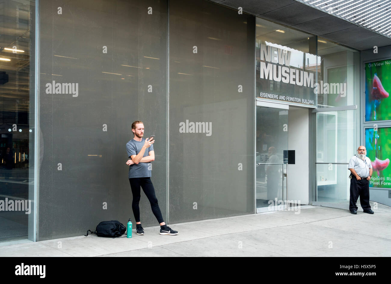 Ein Wachmann, der Blick auf eine männliche Hipster Beratung sein Smartphone im neuen Museum Stockfoto