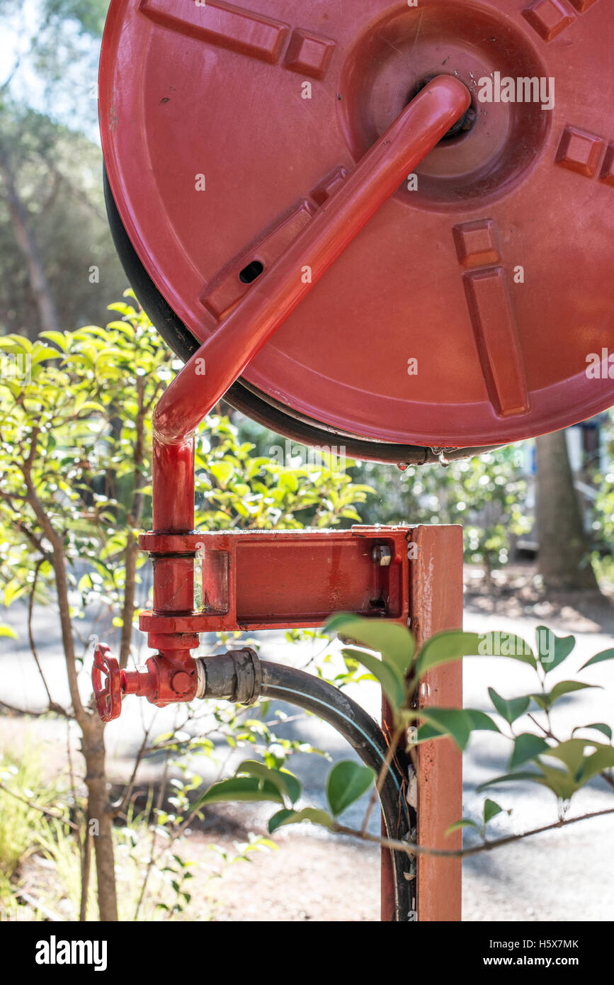 Feuerlöscher in einem Garten. Bäume und Häuser Stockfoto