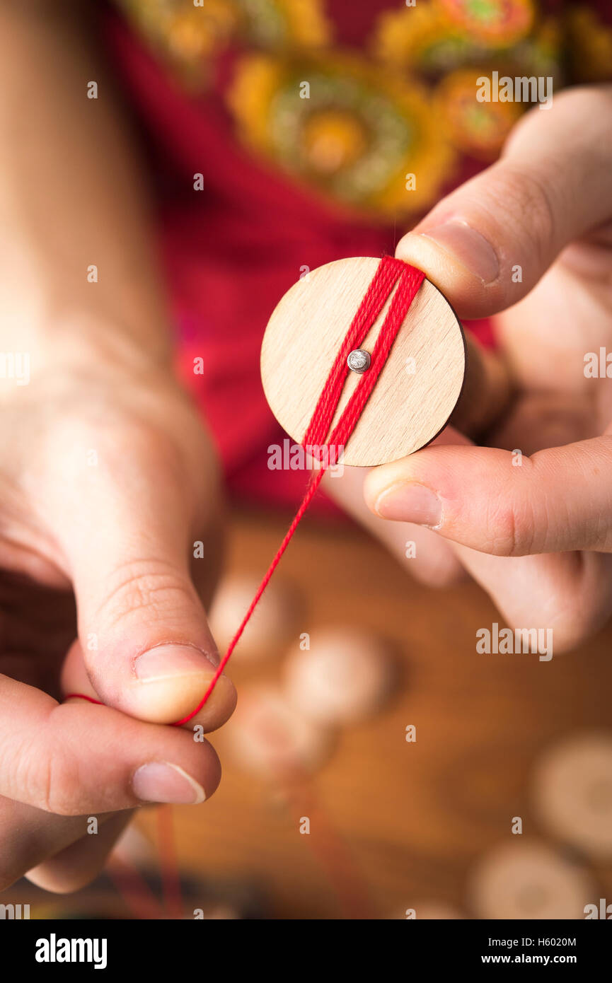 Button-Maker im zweiten Schritt der Posamentenknöpfe Erzeugerbetrieb hölzerne leer und sorgfältig Umhüllung rotes Garn Stockfoto