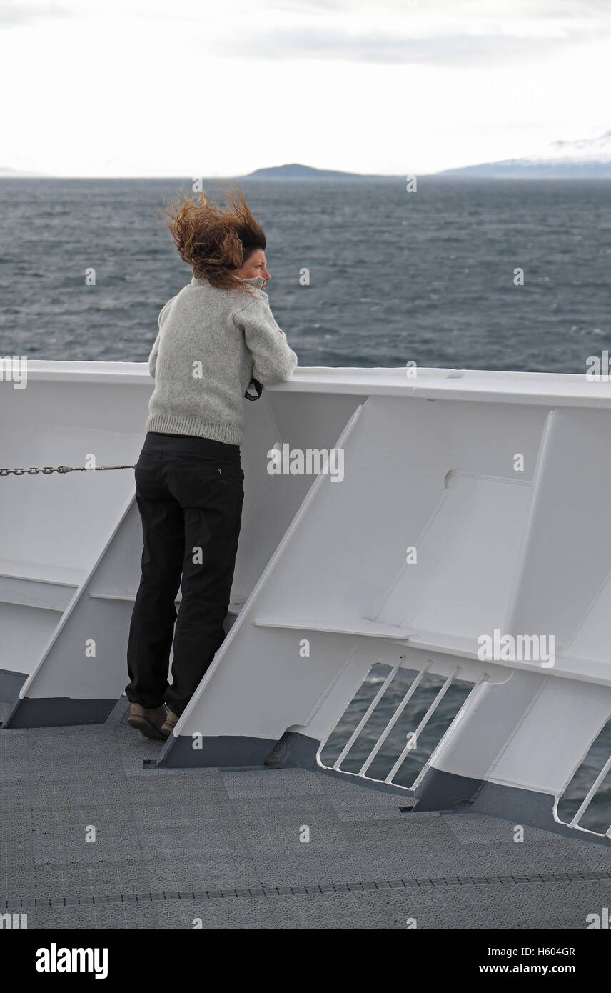 Starker Wind weht eine Frau an den Haaren, auf einem Schiff vor der Küste von Island. Stockfoto