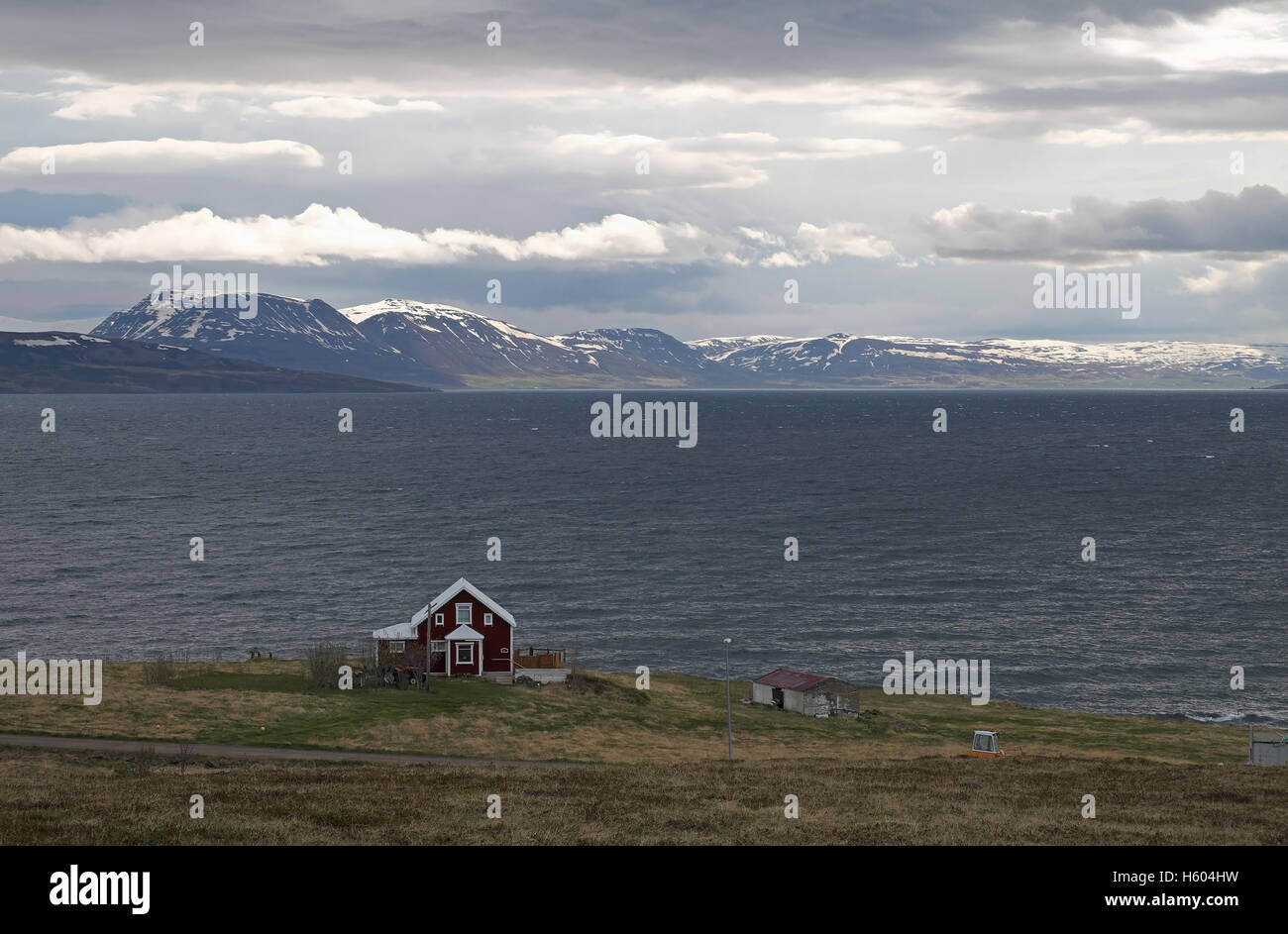 Einsame Haus auf der Insel Hrisey, mit Schnee bedeckt Berge, Eyjafjordur, nördlich von Akuretri, Island. Stockfoto