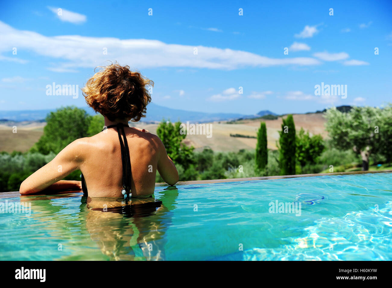 Eine Frau von hinten bewundern die toskanische Landschaft in den Pool von Fonteverde Natural Spa Resort in San Casciano dei Bagni Stockfoto