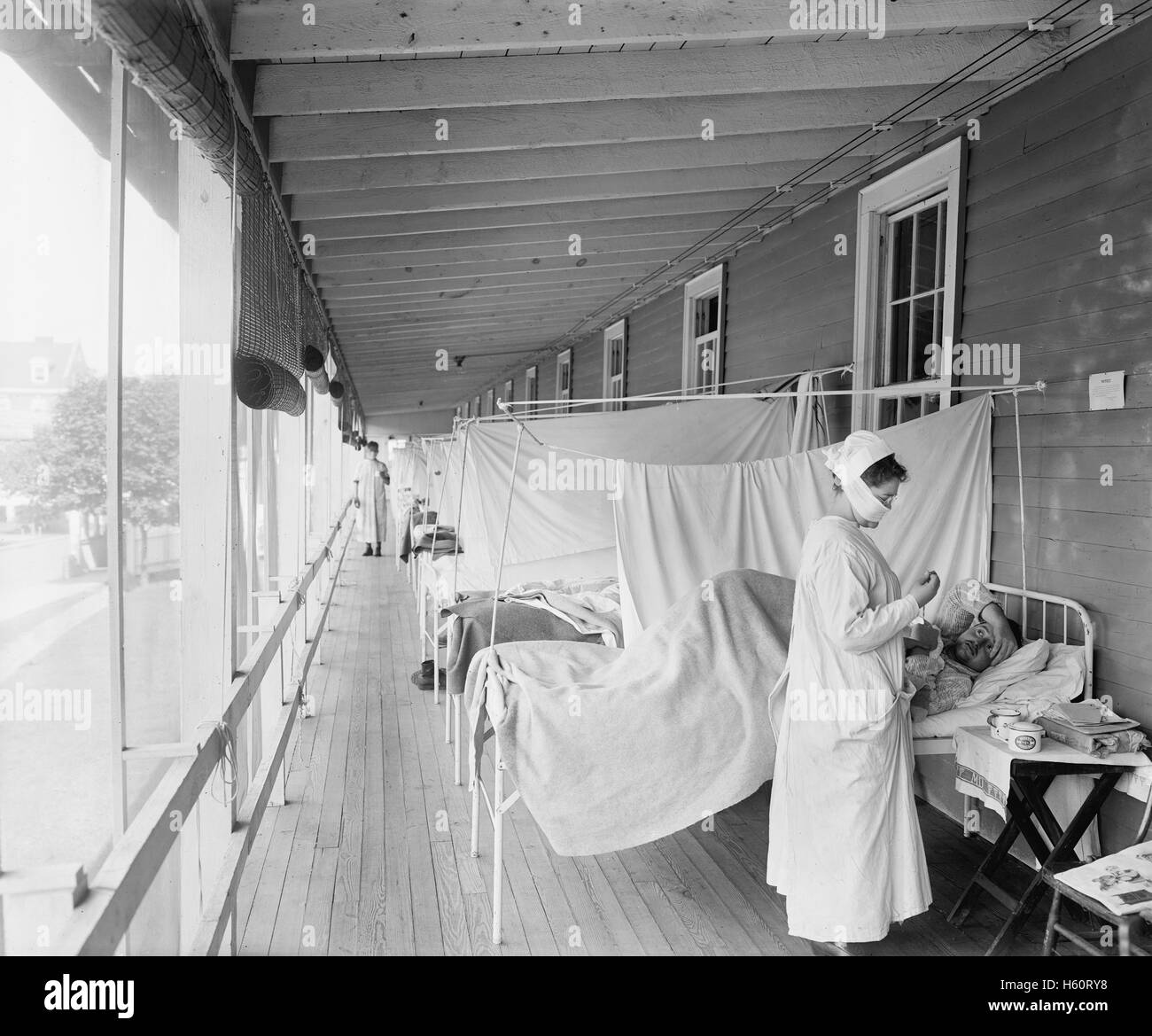 Maskierte Krankenschwester an der Spitze einer Reihe von Betten, die Behandlung von Patienten während der Influenza-Pandemie, Walter Reed Hospital, Washington DC, USA, Harris & Ewing, 1918 Stockfoto