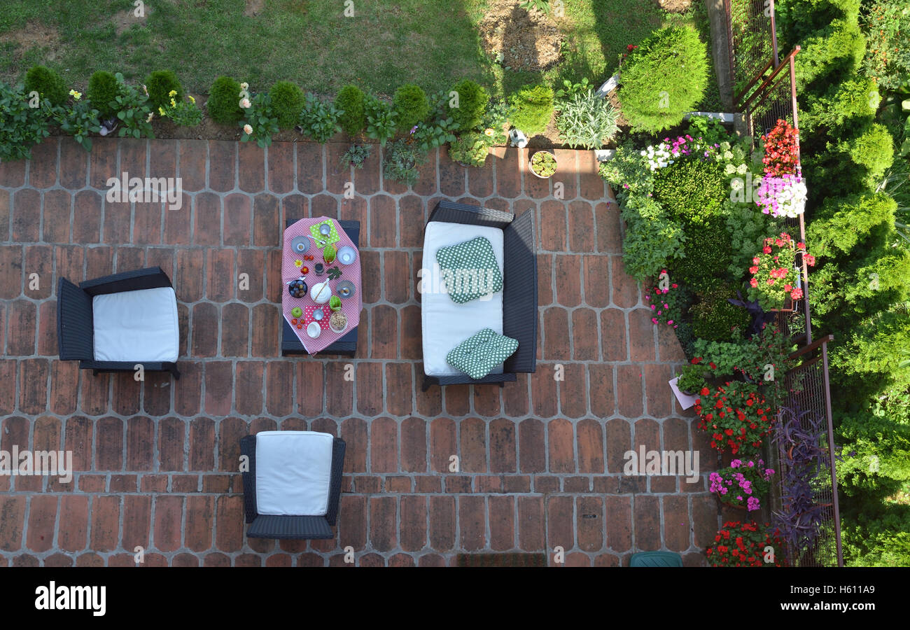 Vogelperspektive von Gartenmöbeln mit bedienten Tisch, umgeben von Blumen und Pflanzen Stockfoto