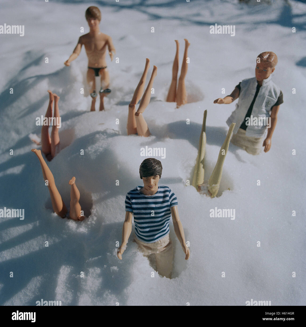 Barbie-Puppen kopfüber im Schnee mit Ken Puppen Stockfoto