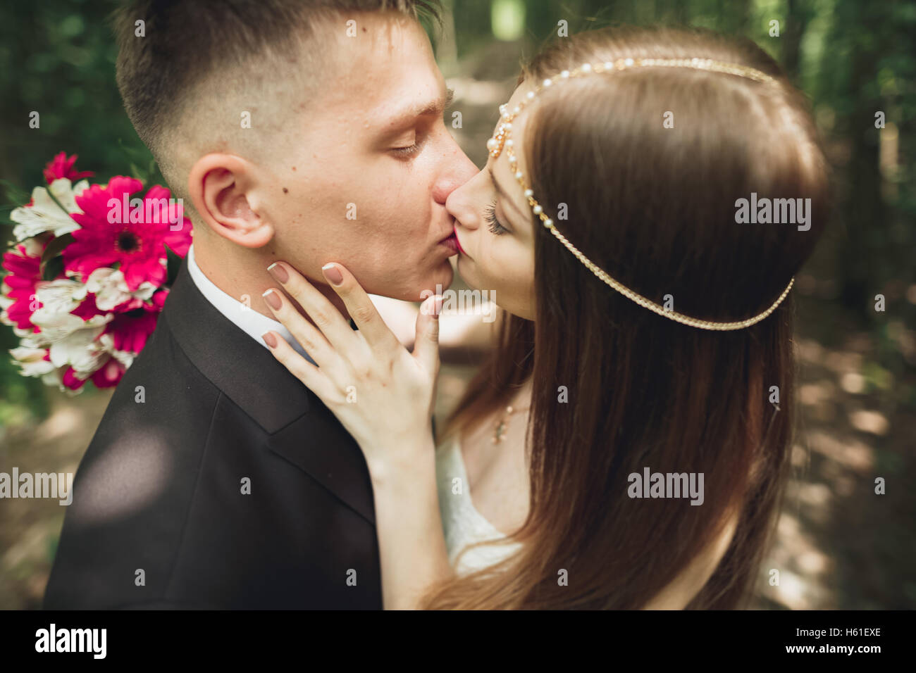 Schöne junge Brautpaar küsst und lächelnd in den park Stockfoto