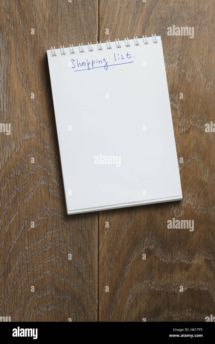 Einkaufsliste auf Notizblock auf Holztisch Stockfoto