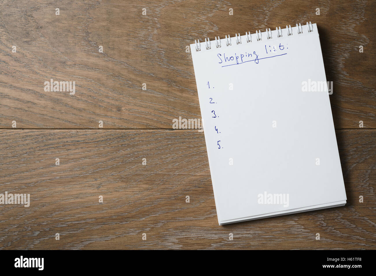 Einkaufsliste auf Notizblock auf Holztisch Stockfoto