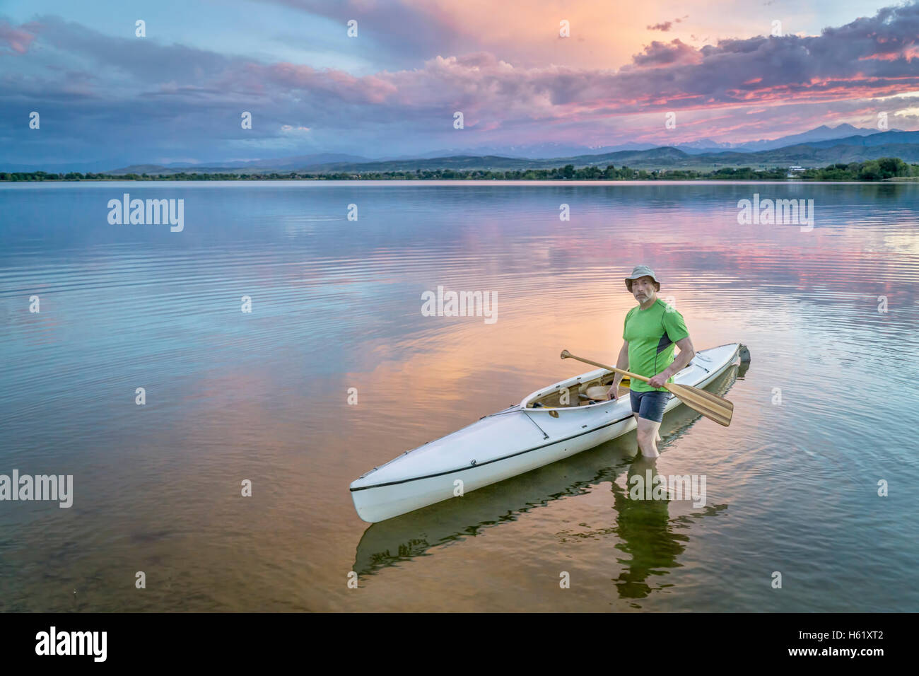 Senior Paddler mit einem geschmückten Expedition Kanu auf einem ruhigen See mit Rocky Mountains und Longs Peak im Hintergrund Stockfoto