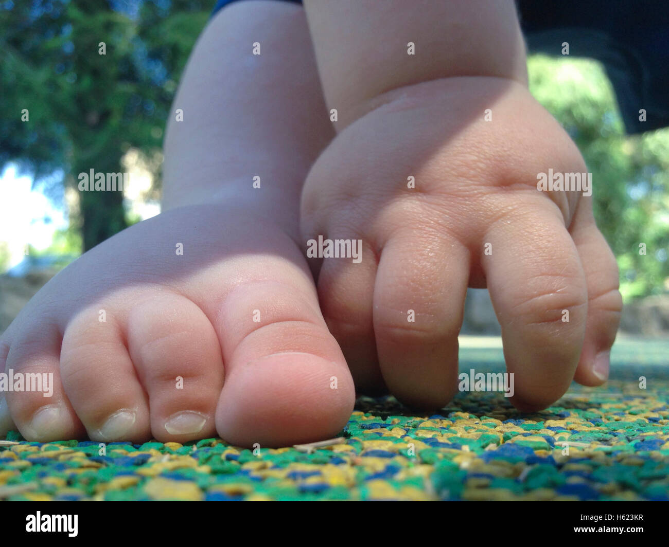 11 Monate altes Baby Boy Fuß und Hand über Playpark Gummiboden Stockfoto