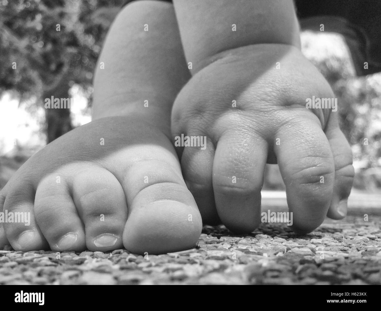 11 Monate altes Baby junge Füße über Playpark Gummiboden. B&W Schuss Stockfoto