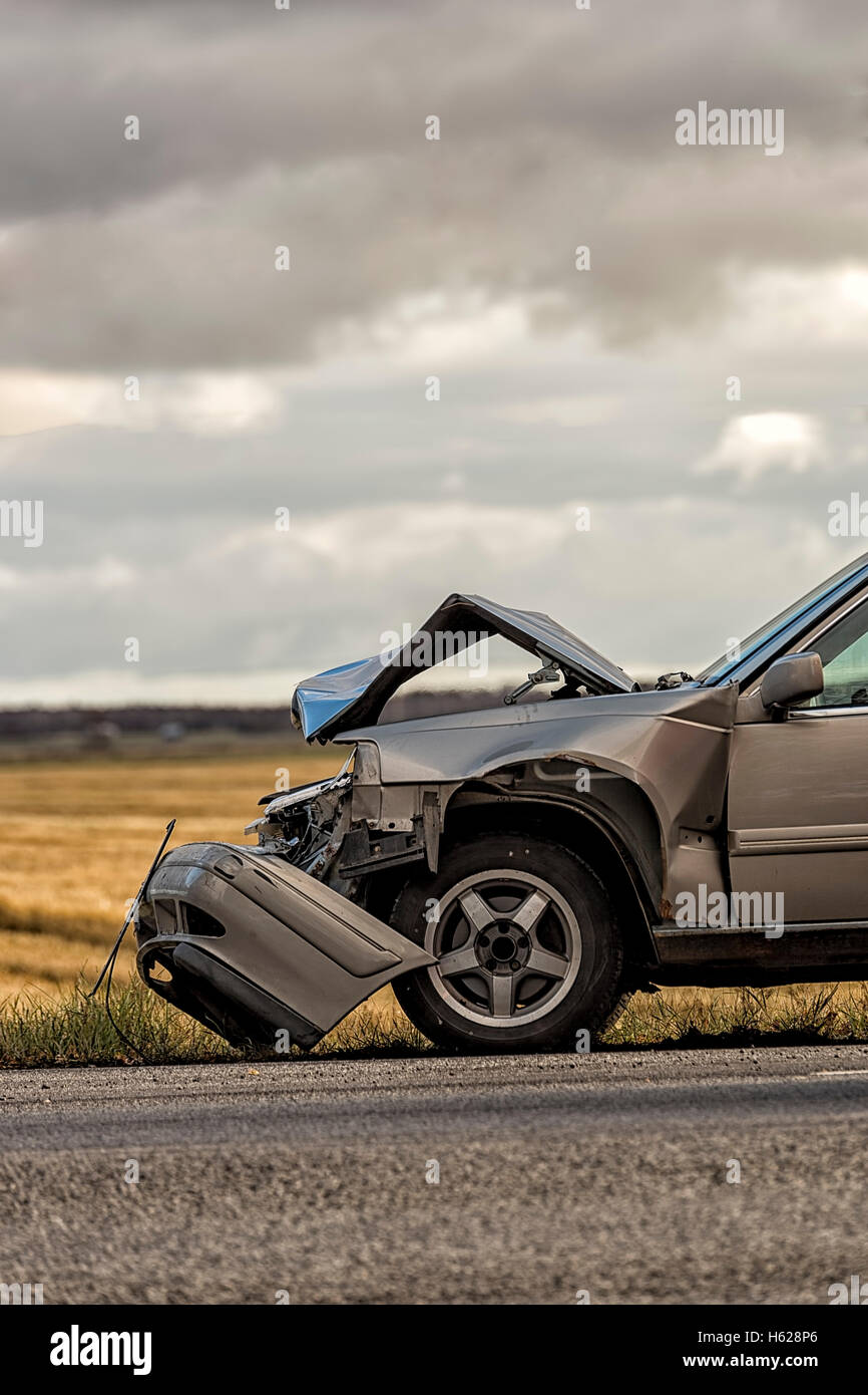 Auto abgestürzt nach Unfall mit einem Feld und bewölktem Himmel. Stockfoto