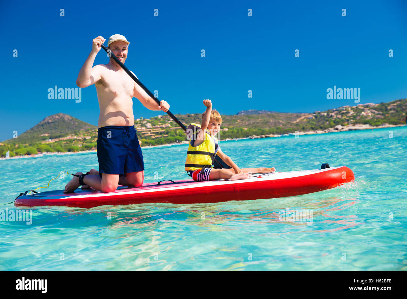 Vater mit wenig glücklich Sohn Spaß auf Stand up Paddle Board auf Korsika, Frankreich. Stockfoto